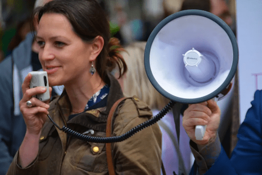 A woman speaks into a megaphone held by a friend.